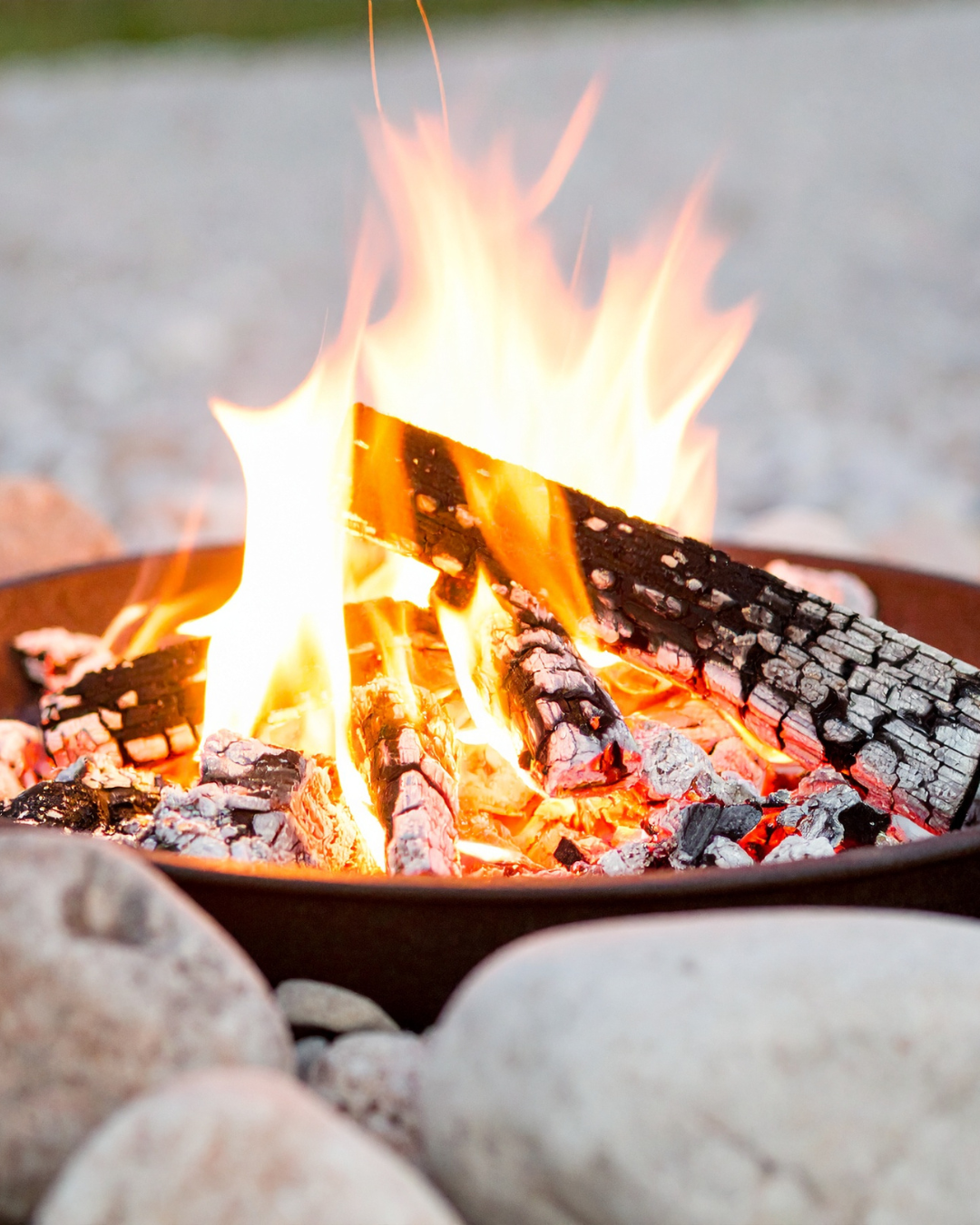 A wood fire burning in an iron fire bowl set among stones